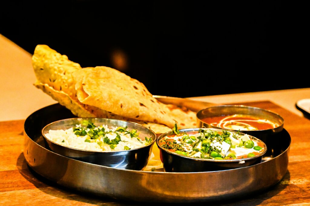 Exquisite Indian thali with naan bread, paneer curry, and aromatic rice served on a wooden table.